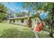 Exterior view of home with stone chimney, wooden stairs, and well-kept lawn at 1335 E 3Rd Ave, Mount Dora, FL 32757