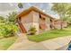 Inviting two-story condo featuring shuttered windows, manicured lawn, mature trees, and a cozy staircase to the entrance at 150 Wax Myrtle Woods Ct # 3D, Deltona, FL 32725