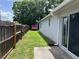 Fenced backyard featuring green grass, lush trees, and a glimpse of a pink chicken coop at 1501 Delaware Ave, St Cloud, FL 34769