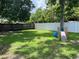 Backyard featuring green grass, trees, and a playset near a white vinyl fence at 1501 Delaware Ave, St Cloud, FL 34769