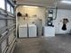 A garage featuring a washer, dryer, water heater, and HVAC system, along with a metal door and shelving at 1501 Delaware Ave, St Cloud, FL 34769
