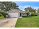 Charming single-story home featuring a manicured lawn, attached garage, and inviting blue front door at 1840 Orange View Ct, Kissimmee, FL 34746