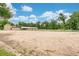 Expansive horse arena with white fencing, stables, and surrounding trees under a bright blue, partly cloudy sky at 2142 Woodbridge Rd, Longwood, FL 32779