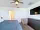 Bedroom with carpeted floor, ceiling fan, television, and dresser with a view of the en suite bathroom at 29783 Anahid Dr, Leesburg, FL 34748