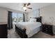 Well-lit bedroom features a black wooden bed frame, neutral walls, and bright natural light from the window at 3172 Jade Tree Pt, Oviedo, FL 32765