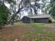 Exterior shot showing a neutral-colored home with a spacious backyard and large trees at 4883 Cherokee Rose Dr, Orlando, FL 32808
