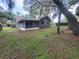 Home exterior featuring a screened porch, neutral paint, green yard and mature trees at 4883 Cherokee Rose Dr, Orlando, FL 32808