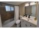 Bathroom featuring tiled shower, neutral walls, white vanity, toilet, black hardware, and framed window at 4883 Cherokee Rose Dr, Orlando, FL 32808
