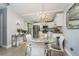 Well-lit kitchen featuring stainless steel appliances, white cabinets, and an elegant glass dining table beneath a chandelier at 5287 Cypress Ct # 724, Orlando, FL 32811