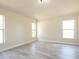 Bright bedroom featuring neutral walls, gray wood floors, and natural light from three windows at 6569 Long Breeze N Rd, Orlando, FL 32810