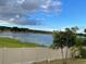 Breathtaking lake view with lush green vegetation and a white fence for privacy under a partly cloudy sky at 6569 Long Breeze N Rd, Orlando, FL 32810