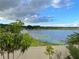 Scenic lake view from the backyard with blue skies, trees, and a partial view of the property's fence at 6569 Long Breeze N Rd, Orlando, FL 32810