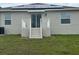 Backyard view featuring a patio with stairs, gray siding, white trim, and solar panels on the roof at 798 Kapi Dr, Groveland, FL 34736