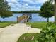 Scenic view of a wooden pier extending into a serene lake, enhanced by lush landscaping and walking path at 8495 Lake Amhurst Trl, Orlando, FL 32829