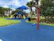 Colorful playground with swings and slides, surrounded by lush landscaping and blue cushioned safety surface at 8495 Lake Amhurst Trl, Orlando, FL 32829