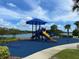 Community playground overlooking a scenic lake, featuring modern play structures and a cushioned surface at 8495 Lake Amhurst Trl, Orlando, FL 32829