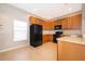 Well-lit kitchen featuring wooden cabinetry, black appliances, and tiled floors for easy maintenance at 9140 Grey Moss Dr, Orlando, FL 32832