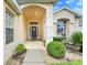 Inviting front entrance with wreath-adorned front door, sidelights, and manicured bushes at 915 Lockbreeze Dr, Davenport, FL 33897