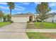 Charming single-story home with a well-manicured lawn, palm tree, and an attached two-car garage at 915 Lockbreeze Dr, Davenport, FL 33897