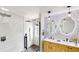 Modern bathroom featuring dual sinks, round mirrors, and walk-in shower with hexagon tile floor at 10747 Satinwood Cir, Orlando, FL 32825