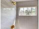 Modern tiled shower featuring an adjustable shower head, controls, and a window with a view at 10747 Satinwood Cir, Orlando, FL 32825