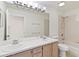 Bright bathroom featuring a double sink vanity and a tiled bathtub at 10828 Cherry Oak Cir, Orlando, FL 32817
