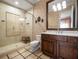 Bathroom with a glass enclosed shower, beige tile, dark cabinets, and decorative wallpaper at 11106 Coniston Way, Windermere, FL 34786