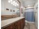 Bathroom with a long vanity, light walls and a walk-in shower with a blue curtain at 11106 Coniston Way, Windermere, FL 34786