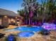 An inviting outdoor space features a pool, spa, rock waterfall, outdoor kitchen, and colorful ambient lighting at 11106 Coniston Way, Windermere, FL 34786
