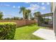 Private backyard featuring lush green grass, a brick wall, palm trees, and a screened in lanai at 1275 Shallcross Ave, Orlando, FL 32828