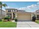 Inviting two-story home featuring a manicured lawn, attached two-car garage, and desert landscaping at 14680 Yorkshire Run Dr, Orlando, FL 32828