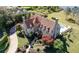 Aerial view of estate featuring a clay tile roof, stone turret, swimming pool, and professionally landscaped grounds at 1477 Shadwell Cir, Lake Mary, FL 32746
