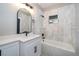 Bathroom featuring white vanity, black fixtures, bathtub with custom shower surround and window at 1505 Delaney Ave, Orlando, FL 32806