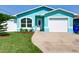 Brightly painted house features a well-maintained lawn and a driveway leading to a single-car garage at 1618 Oregon Ave, St Cloud, FL 34769