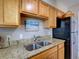 Kitchen featuring wooden cabinets, granite countertops, and stainless steel double sink at 1618 Oregon Ave, St Cloud, FL 34769