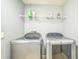 Well-lit laundry room featuring a modern washer, dryer, and shelf for organizing essential supplies at 16449 Cedar Crest Dr, Orlando, FL 32828