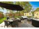 An outdoor patio with stone pavers, comfortable seating, a dining table and chairs, and an umbrella for shade at 1649 W Waycross Cir, Deltona, FL 32725