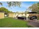 An outdoor patio with stone pavers, comfortable seating, a dining table, an umbrella, and a well-kept yard at 1649 W Waycross Cir, Deltona, FL 32725