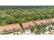Aerial view of modern townhomes with tile roofs, surrounded by green trees and overlooking a tranquil pond at 1852 Garden Sage Dr, Oviedo, FL 32765