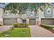 Townhouse exterior featuring gray stucco, brick driveway, and a beautiful shrub in front at 1852 Garden Sage Dr, Oviedo, FL 32765