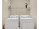 Bright laundry room featuring a white washer and dryer, complemented by functional shelving and ample storage space at 1852 Garden Sage Dr, Oviedo, FL 32765
