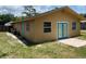Exterior view of home's backyard showcasing the stucco siding, blue door, and well-maintained lawn at 211 Valencia Rd, Debary, FL 32713