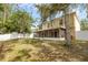 View of the backyard with mature trees, a white fence, grass, and an enclosed patio at 2255 Tealwood Cir, Tavares, FL 32778