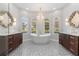 Luxury bathroom featuring dual vanities, a freestanding tub, decorative tile flooring and arched windows at 23538 Valderama Ln, Sorrento, FL 32776