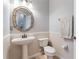 Powder room featuring a pedestal sink, decorative mirror, and a toilet at 23538 Valderama Ln, Sorrento, FL 32776