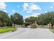 Gated community entrance with stone pillars, decorative gates, and lush landscaping at 23538 Valderama Ln, Sorrento, FL 32776