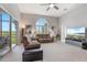 Spacious living room with ceiling fan, large window, comfortable couches, and a TV at 23538 Valderama Ln, Sorrento, FL 32776