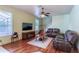 Open living room with hardwood floors, stairs, TV, ceiling fan, and comfortable leather seating at 2406 Blossomwood Dr, Oviedo, FL 32765