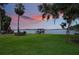 Green lawn with waterfront views, mature trees and a charming chimney and dock at 2652 Lake Howell Ln, Winter Park, FL 32792