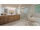 Bright bathroom with wooden cabinets, twin sinks, glass shower, and tub at 2652 Lake Howell Ln, Winter Park, FL 32792